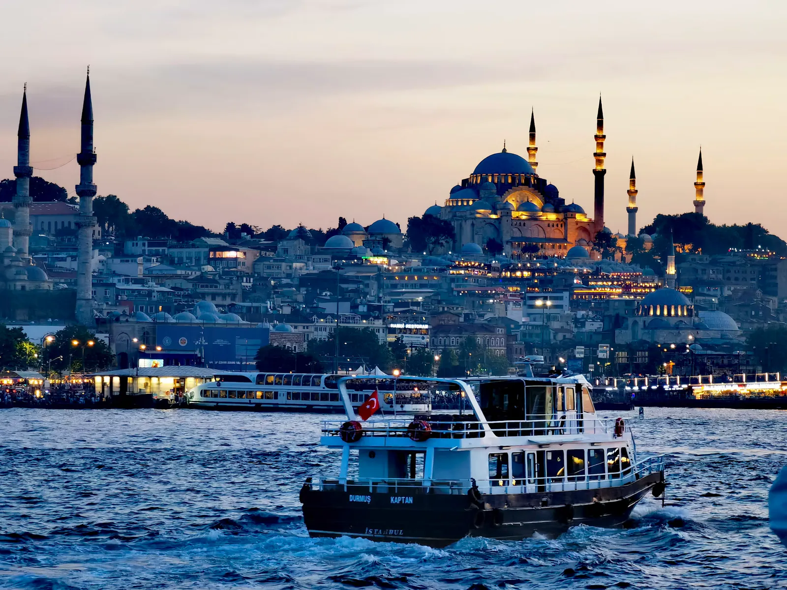 Istanbul's skyline at dusk, with a ferry crossing the Bosphorus